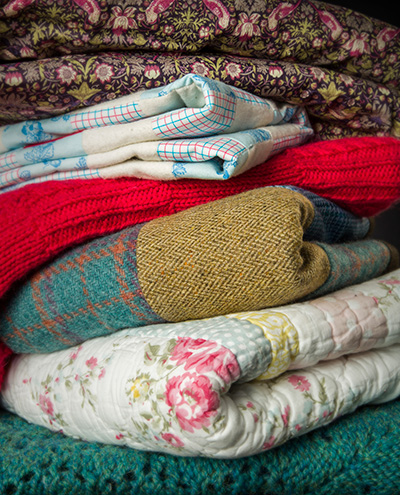 Pile of different coloured and textured quilts